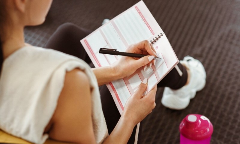 Žena piše u svesku plan treninga